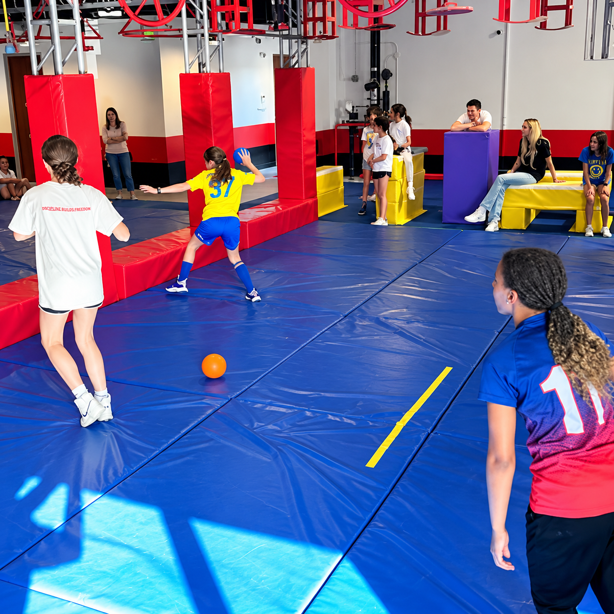 Kids playing a game with a ball on the blue mats at Ninja Republic in San Mateo, California