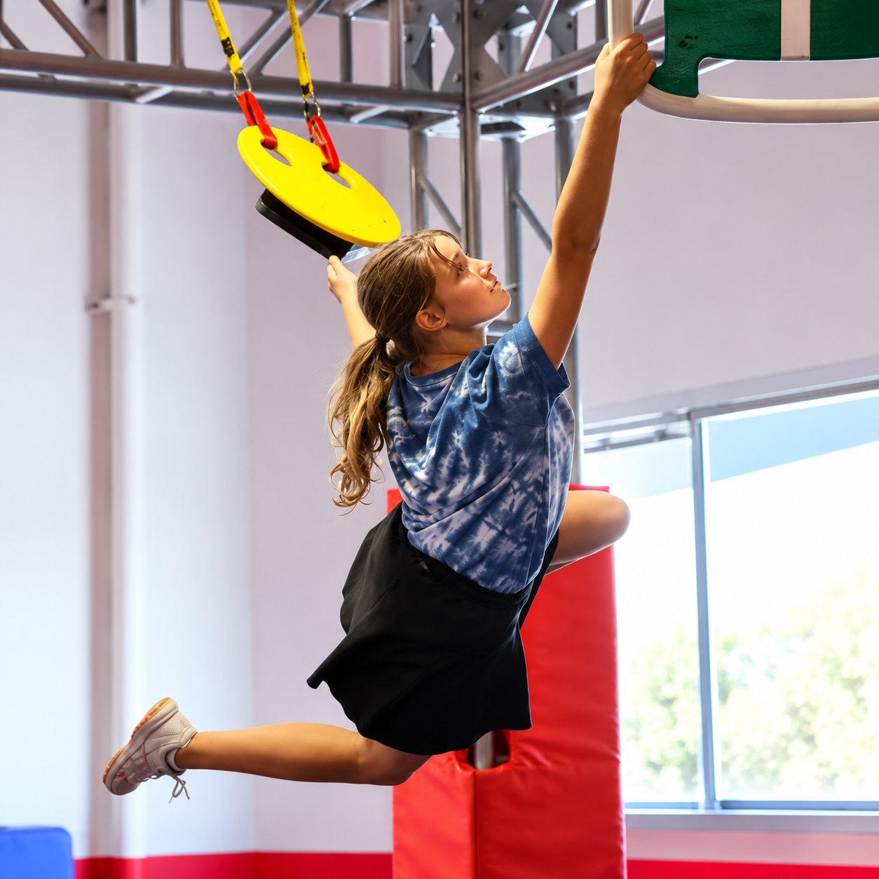 Young athlete swinging from a hanging obstacle at Ninja Republic in San Mateo, California