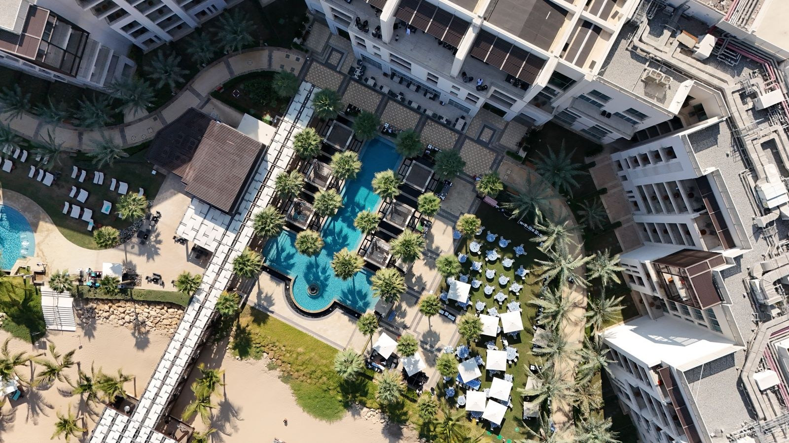 Aerial view of a resort with pools and palm trees in Muscat, Oman