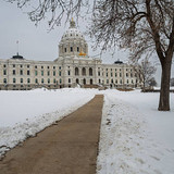 Minnesota State Capitol building with snow covering the grounds and a clear path leading to the entr
