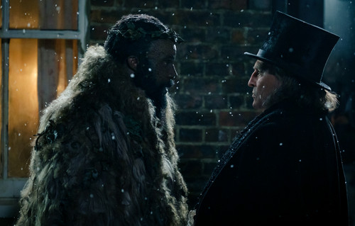 Tramell Tillman plays Ghost of Christmas Present and Johnny Depp plays Ebenezer Scrooge in Ebenezer 