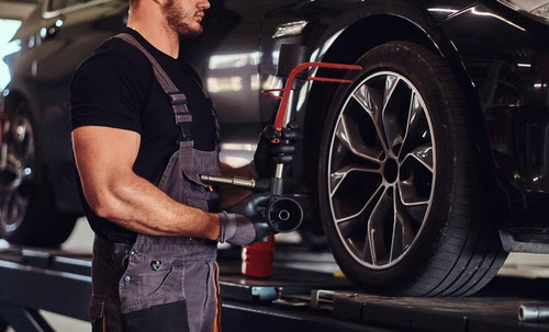 muscular man is fixing car s wheel with special tool auto service 613910 17086.jpg
