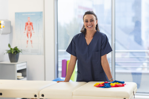 portrait happy female caucasian physiotherapist wearing scrubs hospital.jpg