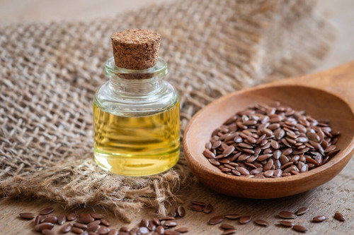 Flaxseed oil in bottle and brown flax seeds on wooden spoon.jpg