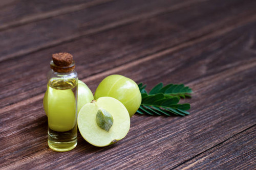 Amla oil and indian gooseberry with green leaves isolated on wooden table background..jpg