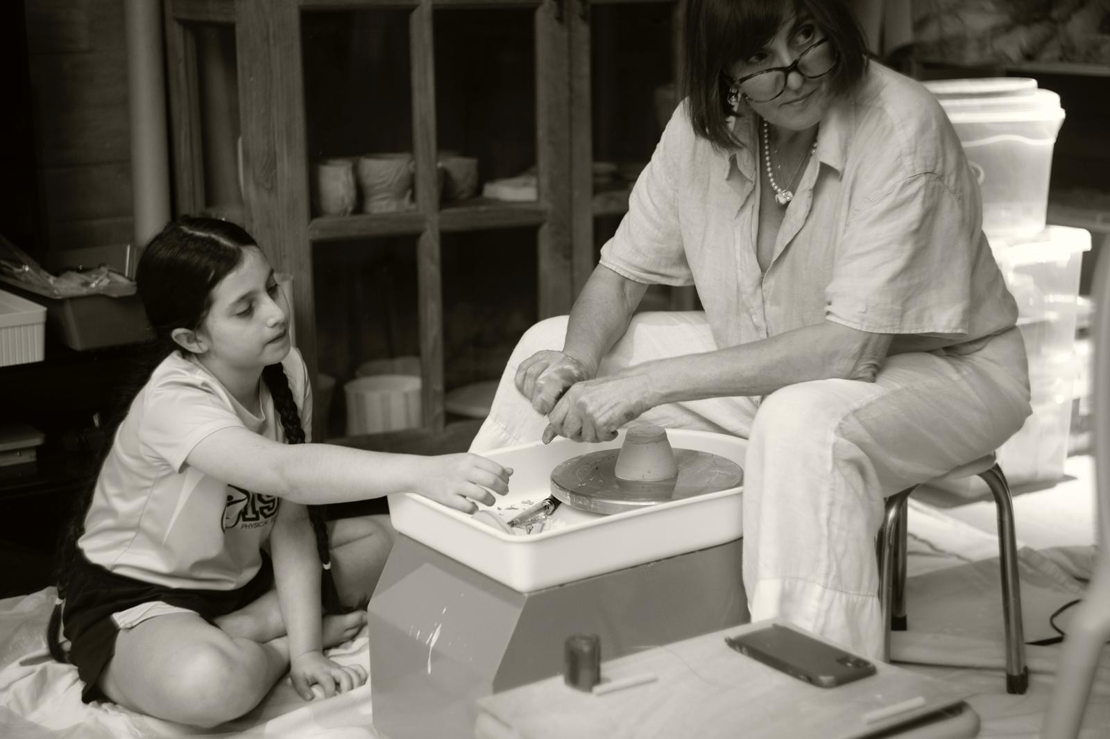 Mother and daughter working together at the pottery wheel