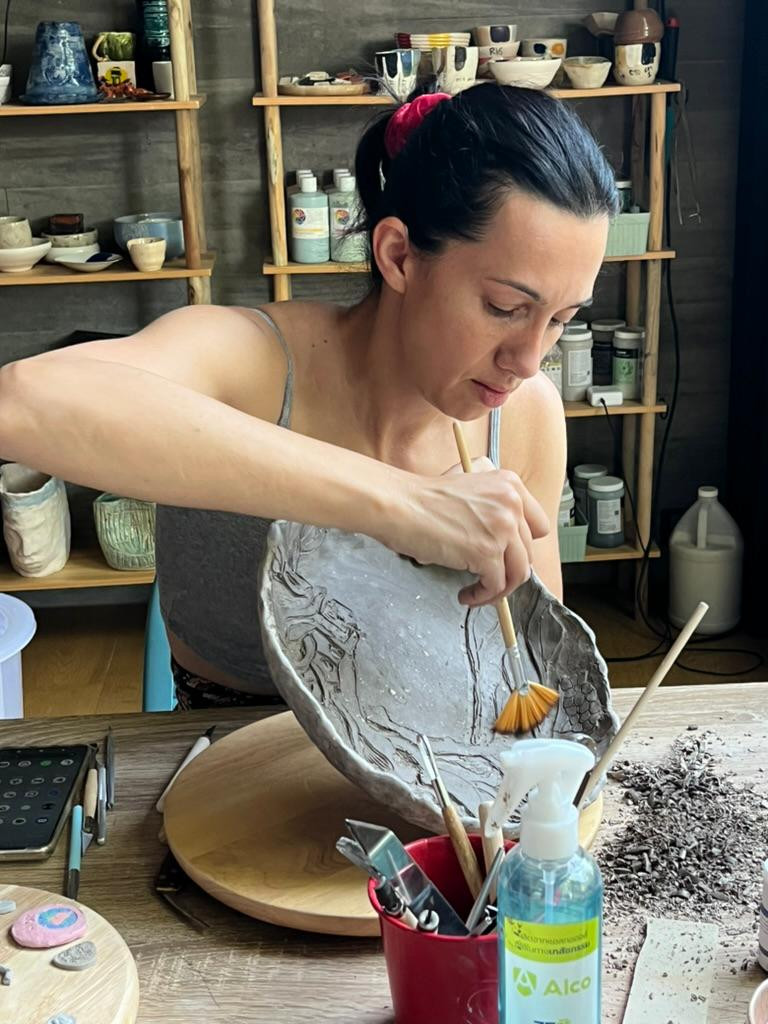 Carving details into a large clay plate
