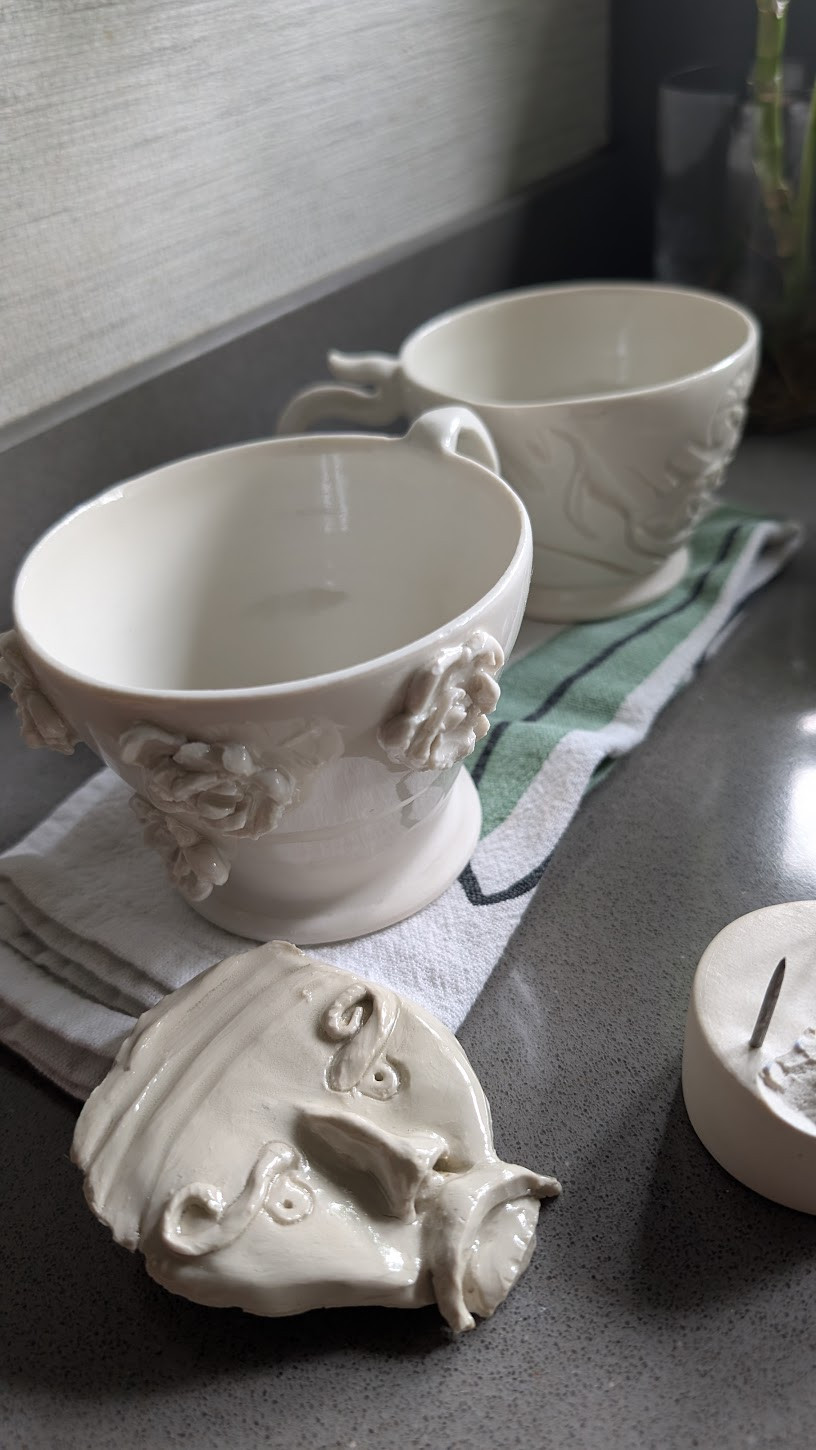 White sculptural cups with rose details after glaze firing