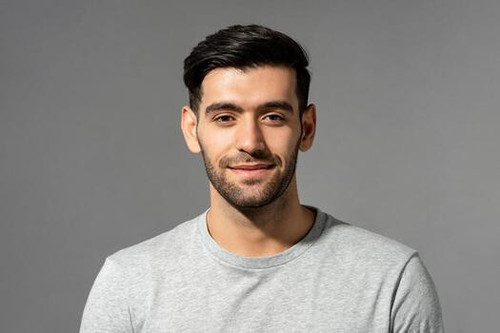 close up portrait of smiling handsome young caucasian man face looking at camera on isolated light g.jpg