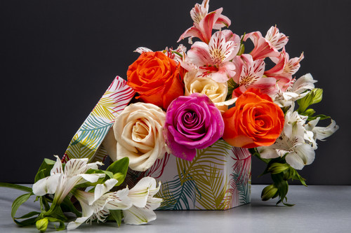 side view of a bouquet of colorful roses and pink color alstroemeria flowers in a gift box on black .jpg