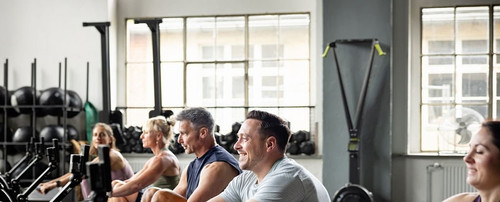A close-up view shows male and female athletes rowing together, smiling and concentrated. The moment.jpg