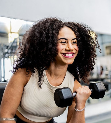 Young woman exercising biceps with dumbbells at the gym.jpg