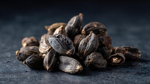 a pile of black cardamom pods on a dark textured surface free photo.jpg