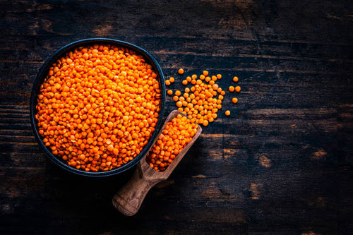 Legumes: Red lentils in a black bowl shot from above on dark wooden table. A serving scoop with lent.jpg