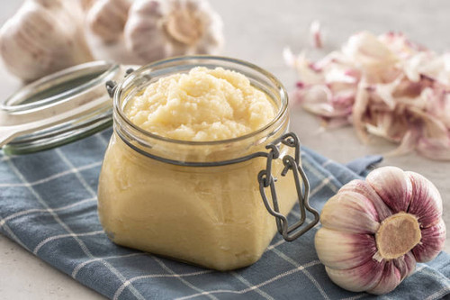 Aromatic garlic paste in a glass jar laid on rustic kitchen cloth with bulbs and peeled cloves..jpg