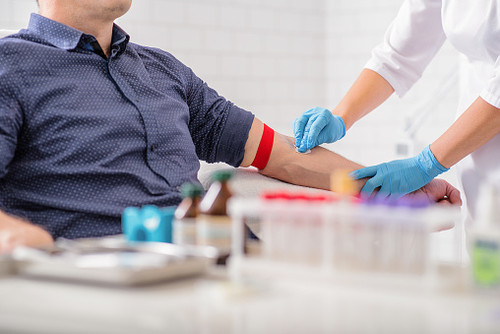 Close up of nurse disinfecting male arm before blood test. Man is sitting on chair near medical set.jpg