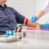 Close up of nurse disinfecting male arm before blood test. Man is sitting on chair near medical set
