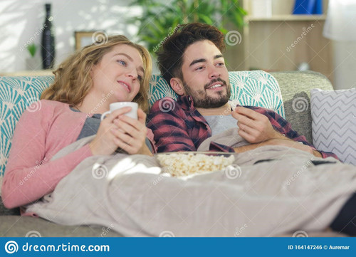 couple sous couverture sur canapé devant la télévision une le qui regarde 164147246.jpg